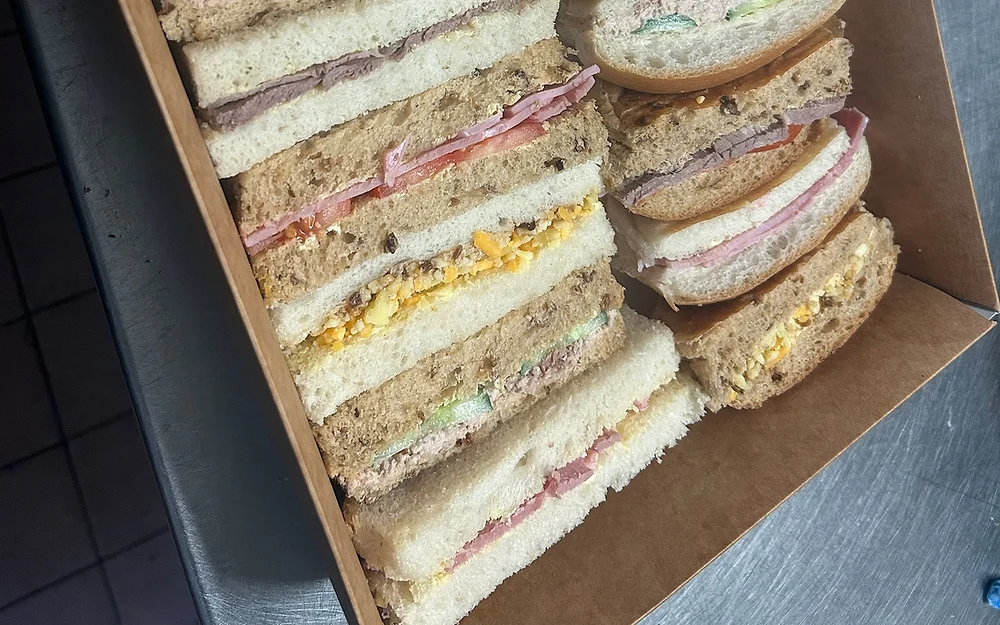 An open catering box of freshly made Wedges Bakery sandwiches, sliced and arranged for sharing